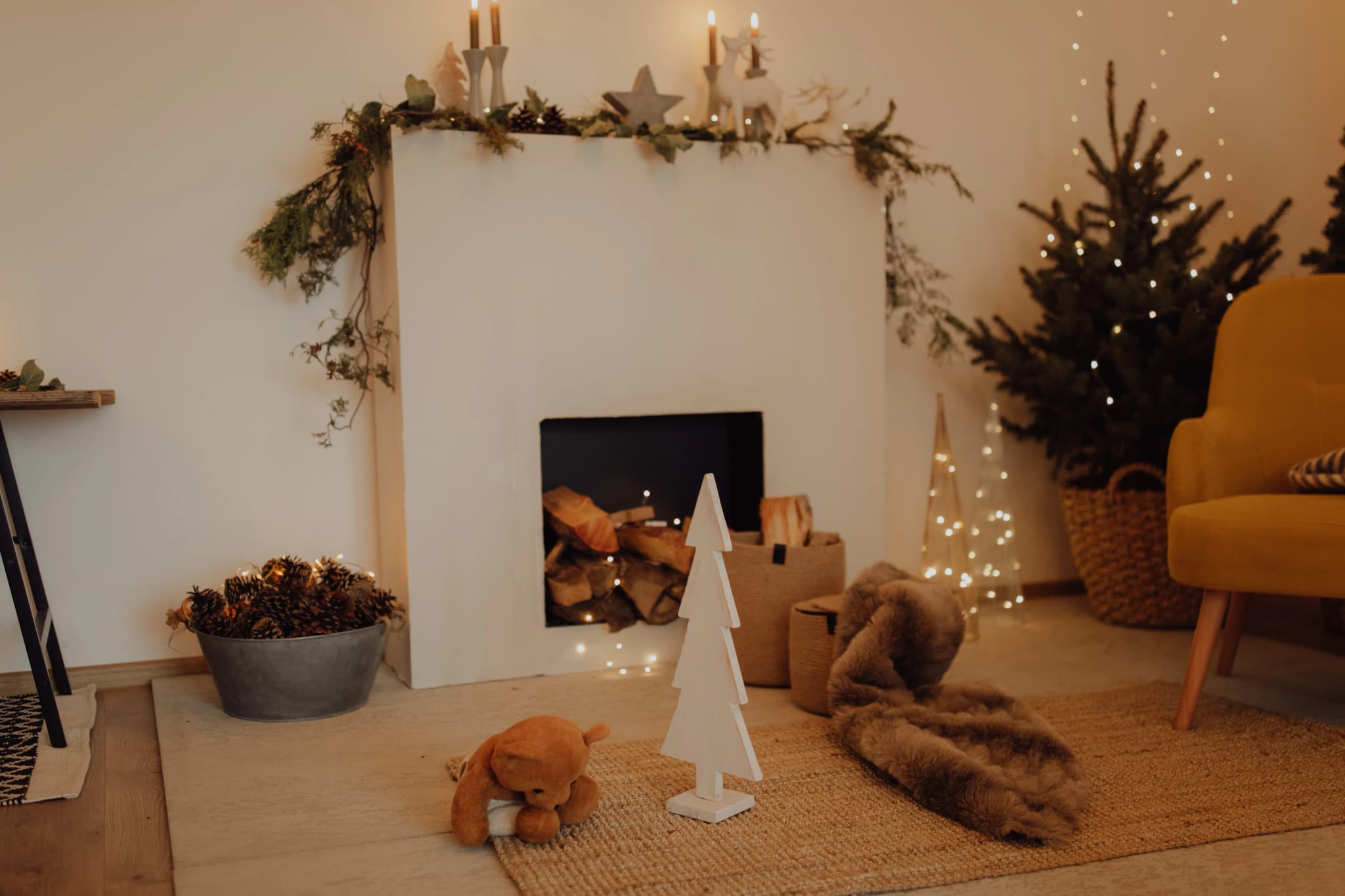 Aufgeräumtes Wohnzimmer mit weihnachtlicher Dekoration, Kerzen und Girlande am Kamin