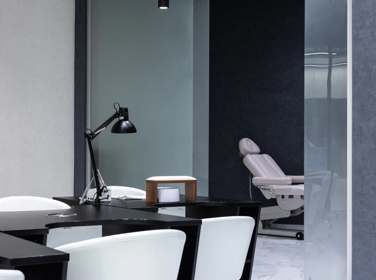 Manikürtische mit Arbeitsleuchte und Behandlungsliege in einem hellen Kosmetikstudio
