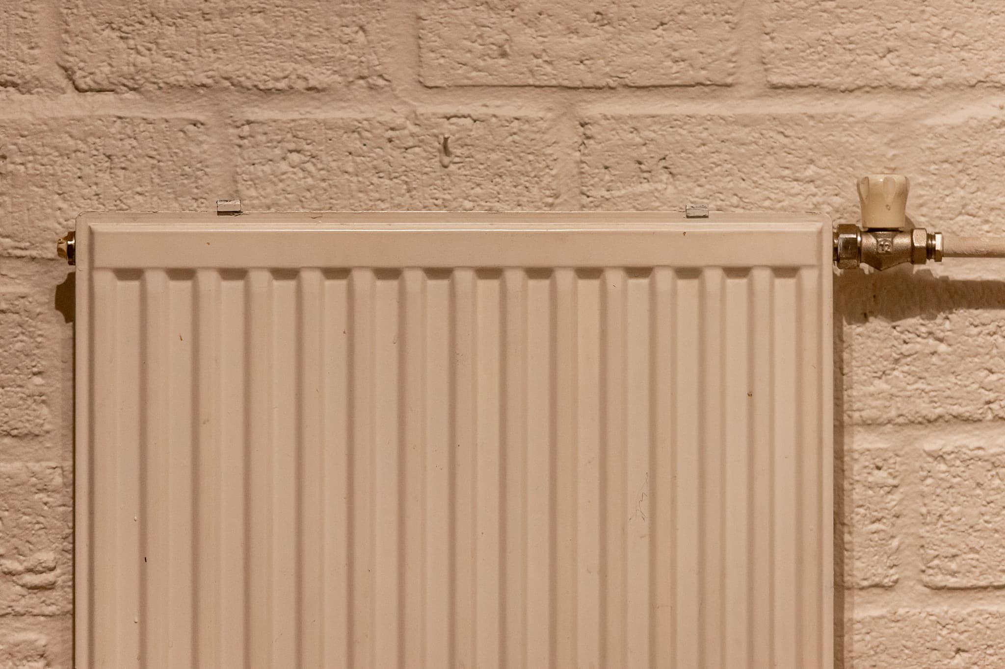 Weißer Heizkörper an einer hellen Wand in einem aufgeräumten Innenraum
