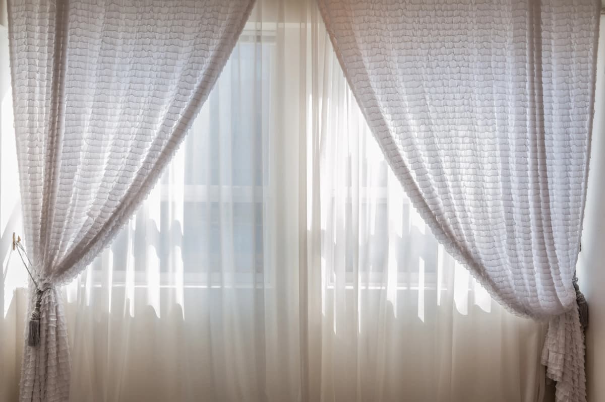 Sonnenlicht fällt durch weiße Vorhänge in einen hellen Wohnraum