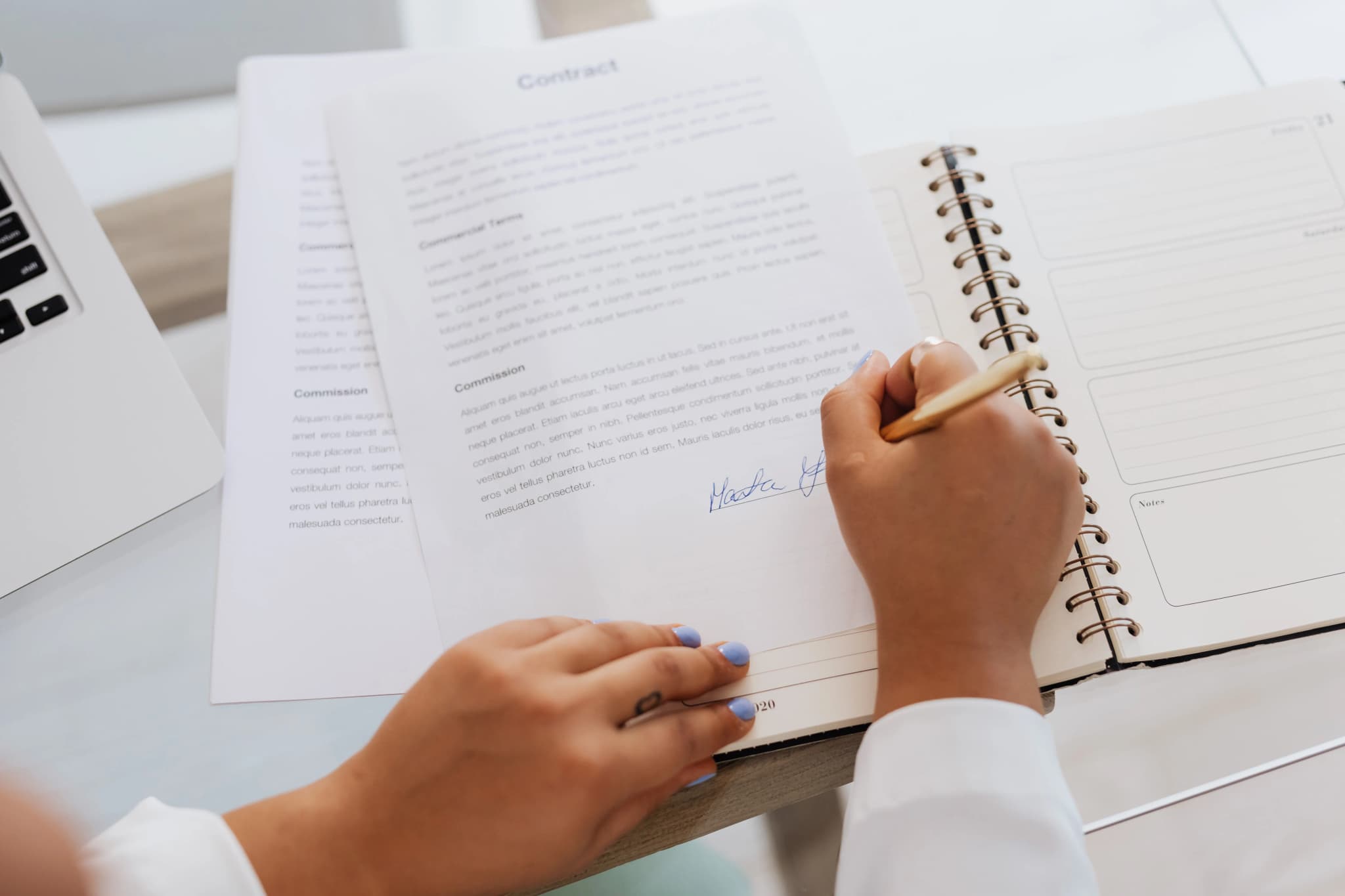 Hände unterzeichnen ein Vertragsdokument auf einem Schreibtisch mit Stift und Unterlagen