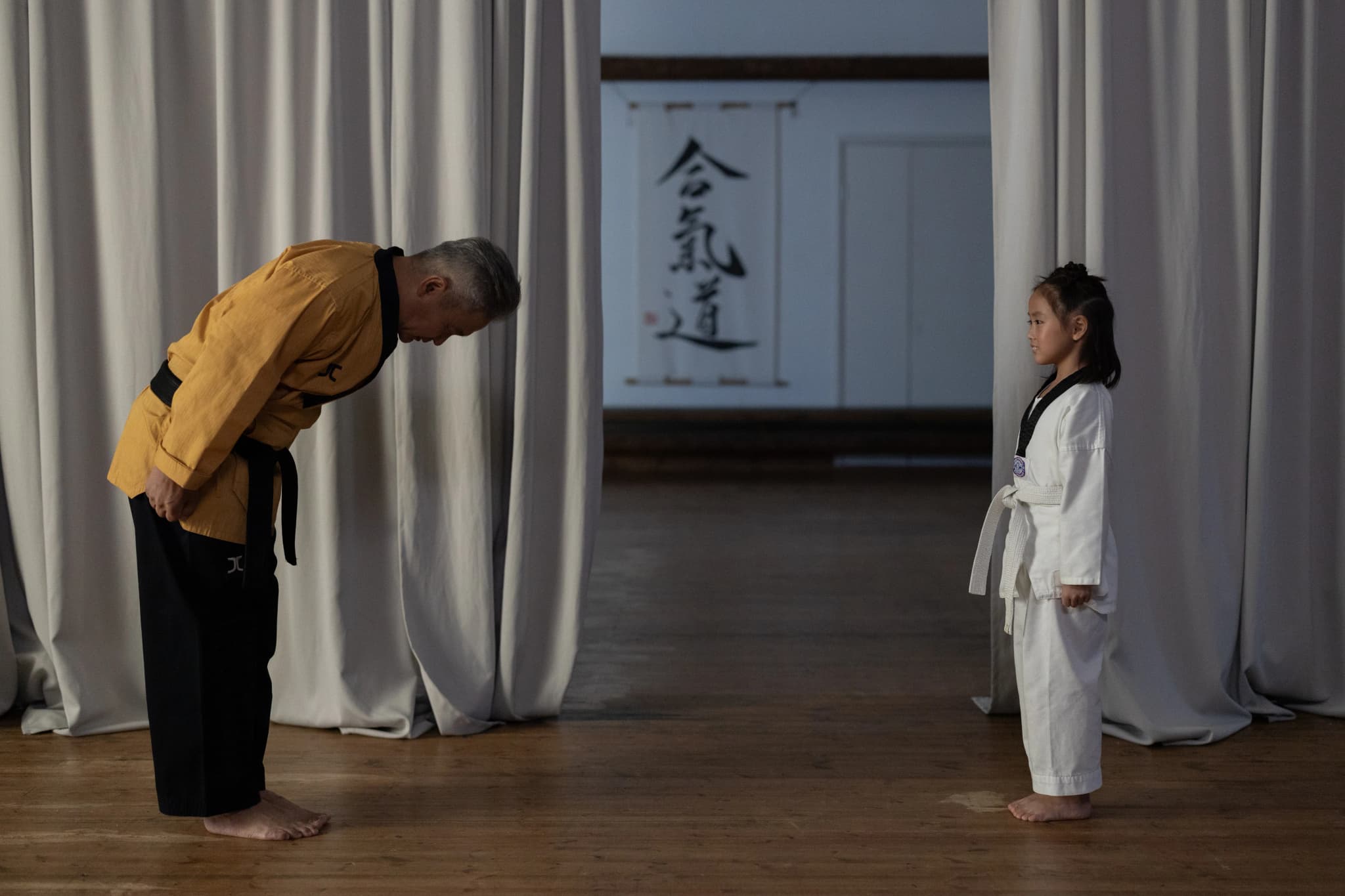 Kampfsportlehrer und Schüler verbeugen sich auf der Trainingsmatte im Dojo