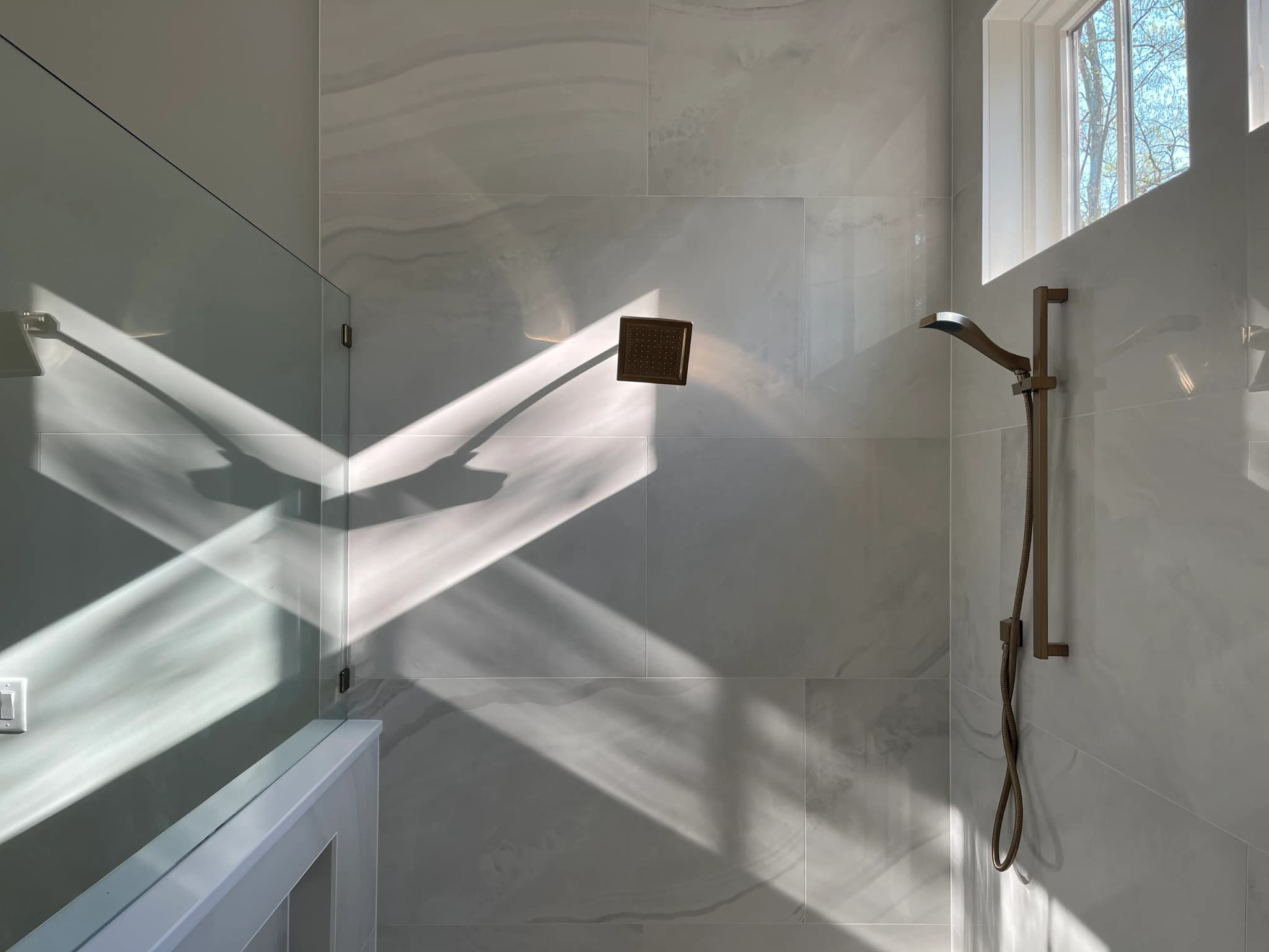 Helles Badezimmer mit gefliester Dusche und Armatur in schlichtem Design