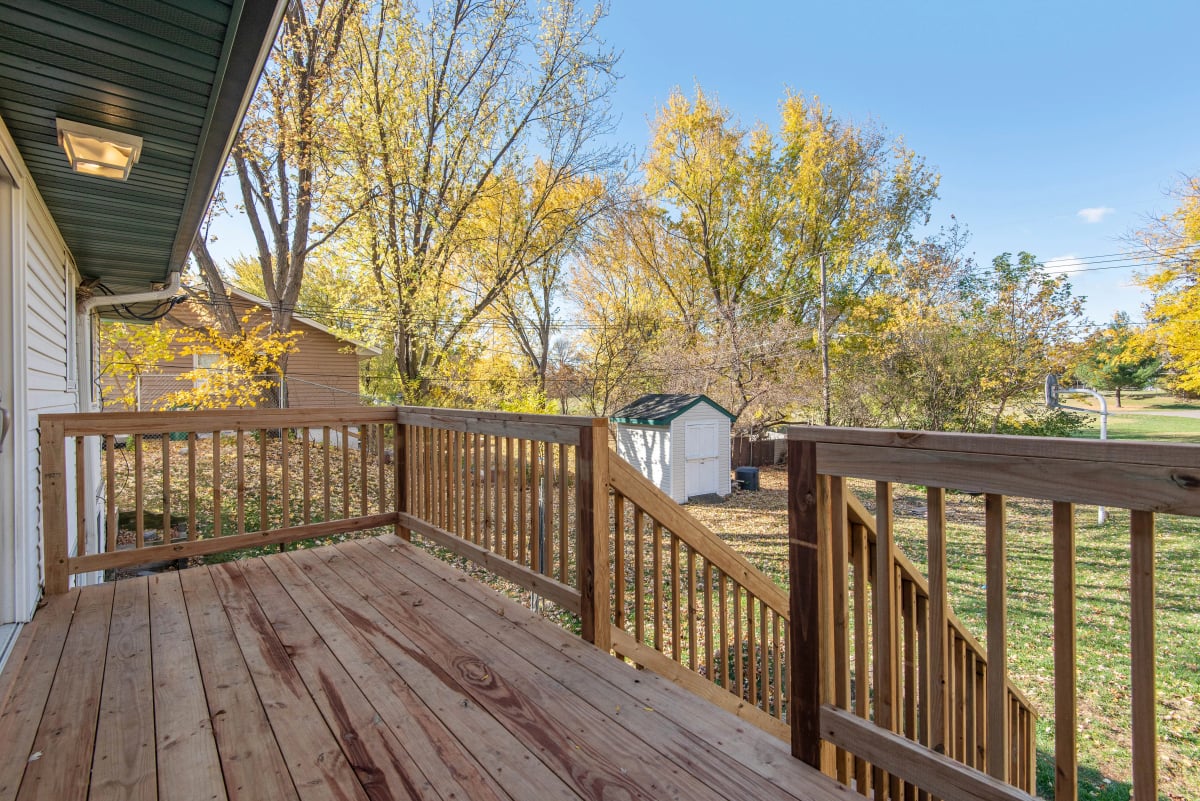 Holzterrasse mit Geländer und Blick in einen herbstlich gefärbten Garten