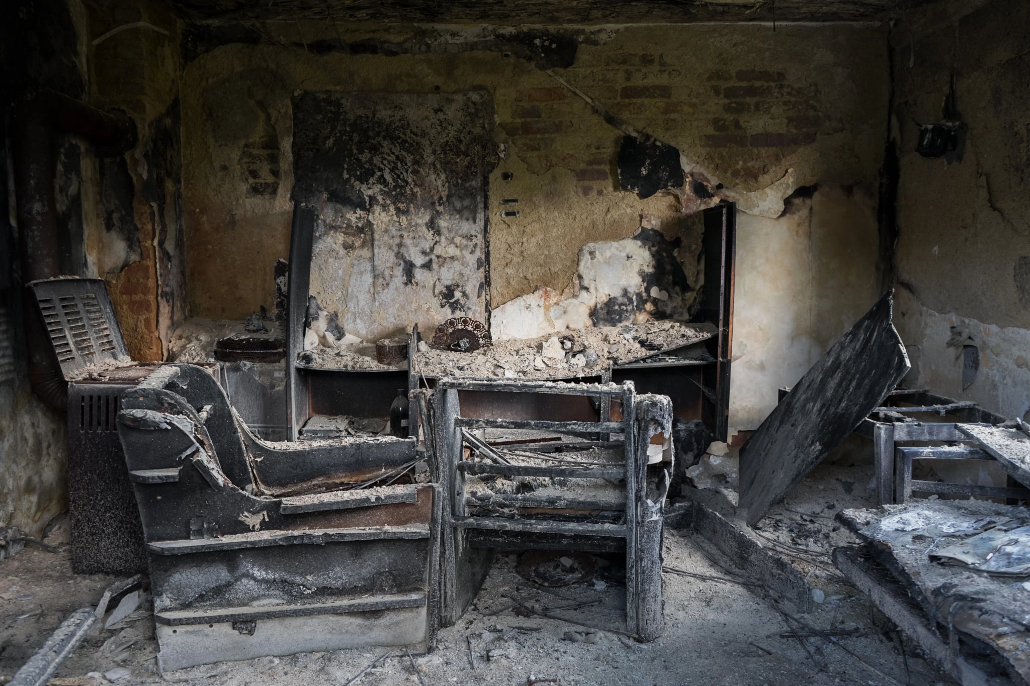 Verrußtes, durch einen Brand beschädigtes Zimmer mit verkohlten Möbeln