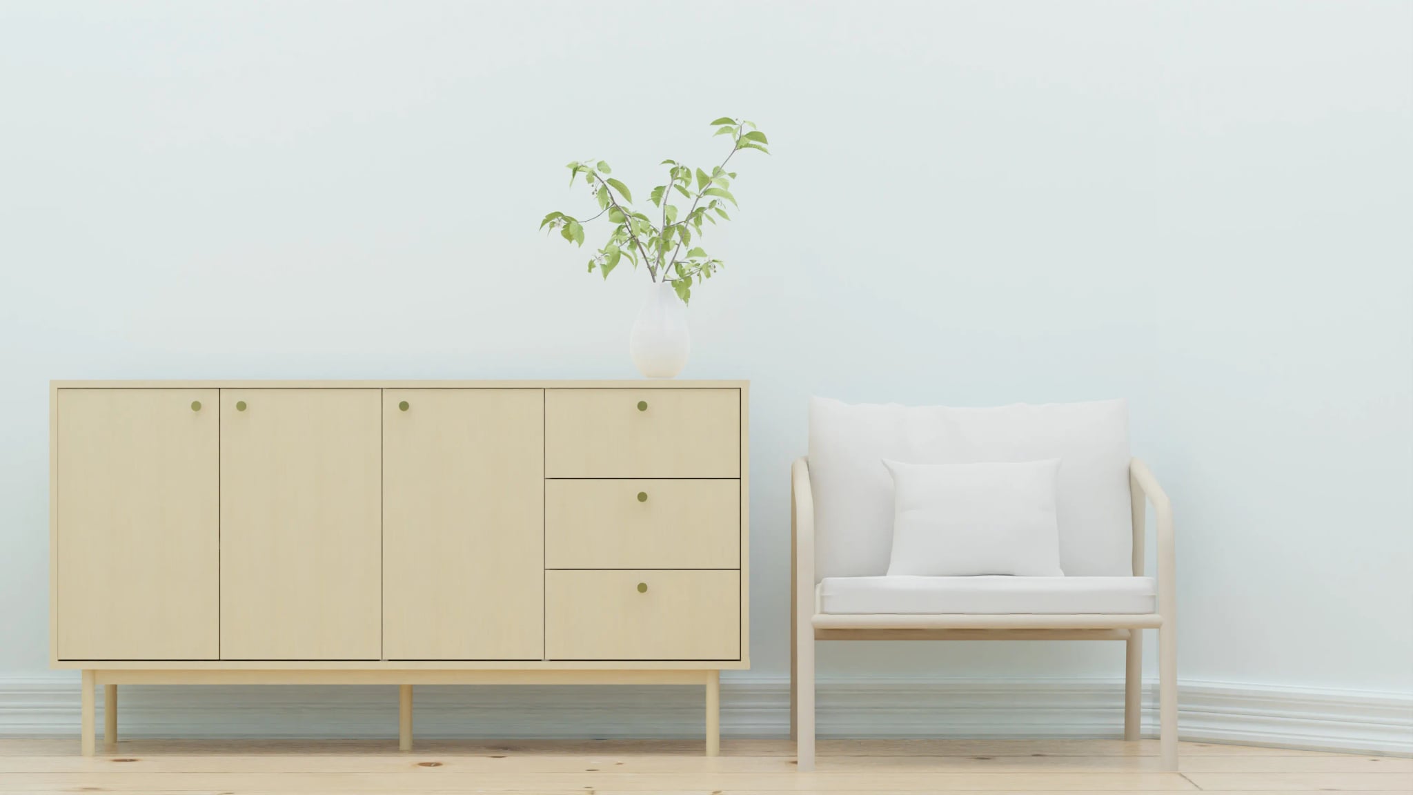 Heller Wohnraum mit Sideboard aus Holz, Sessel und Grünpflanze