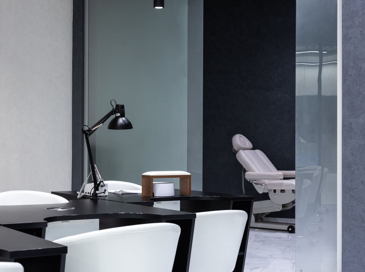 Manikürtische mit Arbeitsleuchte und Behandlungsliege in einem hellen Kosmetikstudio