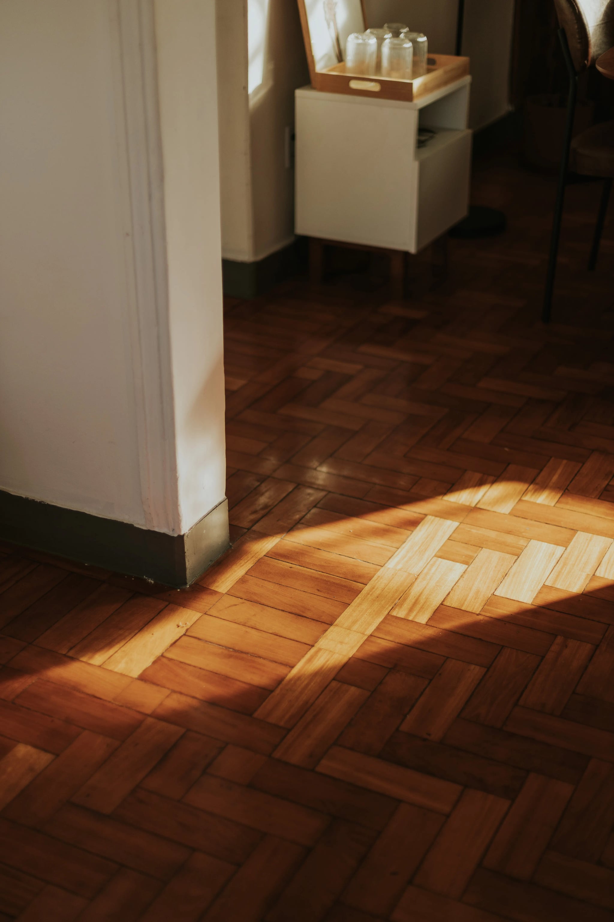 Warmes Sonnenlicht fällt auf einen hölzernen Parkettboden in einem gemütlichen Wohnraum