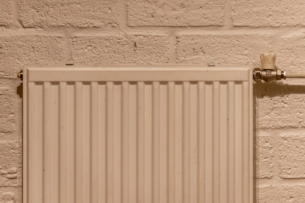 Weißer Heizkörper an einer hellen Wand in einem aufgeräumten Innenraum
