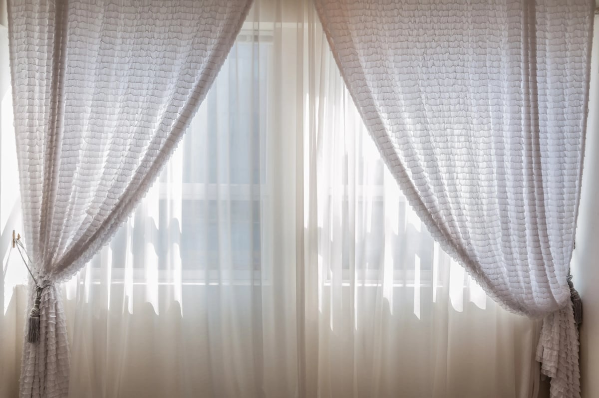 Sonnenlicht fällt durch weiße Vorhänge in einen hellen Wohnraum